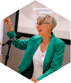 woman in green jacket speaking into a microphone