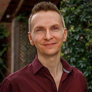 smiling man with short hair and dark red shirt