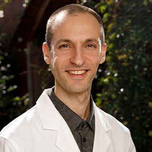 smiling man with short dark hair in white clinic coat